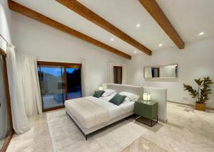Un dormitorio con una cama blanca y una ventana grande. en Villa Horizonte - Luxury Above Puerto de Andratx, en Andratx