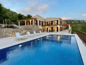 una casa con piscina delante de una casa en Villa Horizonte - Luxury Above Puerto de Andratx, en Andratx
