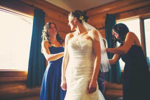 Zwei Frauen helfen einer Braut in ihrem Hochzeitskleid in der Unterkunft Glacier House Hotel & Resort in Revelstoke