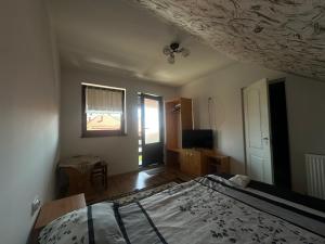 a bedroom with a bed and a window and a television at Korond Mako panzio in Corund