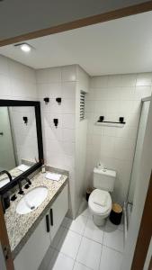 a bathroom with a toilet and two sinks and a mirror at 505 - Studio moderno no Centro-Batel in Curitiba +50 photos