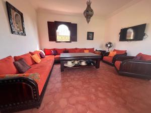ein Wohnzimmer mit einem roten Sofa und einem Fernseher in der Unterkunft Dar Talat in Tahannaout