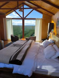 un grand lit dans une chambre avec une grande fenêtre dans l'établissement QHOCHA Titikaka lodge, à Puno