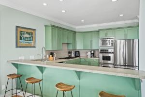 a green kitchen with green cabinets and bar stools at Salty Beach by Coastline Vacation Rentals in Cape San Blas