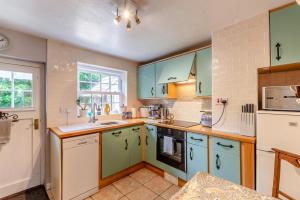 eine Küche mit grünen und weißen Schränken und einer Spüle in der Unterkunft Tail End Cottage in Rye + 11 Fotos