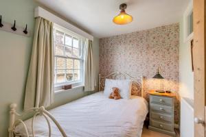 ein Teddybär sitzt auf einem Bett in einem Schlafzimmer in der Unterkunft Tail End Cottage in Rye