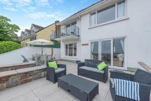 a patio with chairs and tables and an umbrella at Landfall in Saundersfoot