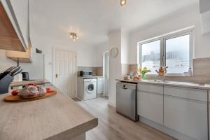 a kitchen with white cabinets and a sink and a table at Landfall in Saundersfoot