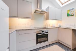 a kitchen with white cabinets and a stove at Seren Fach in Barmouth +6 photos