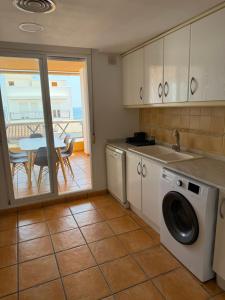 a kitchen with a washing machine and a table with a balcony at Duplex with spacious terraces and stunning sea views, right next to the beach in Jávea