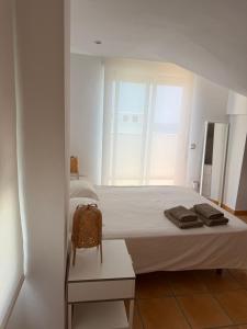 a white bed in a room with a window at Duplex with spacious terraces and stunning sea views, right next to the beach in Jávea
