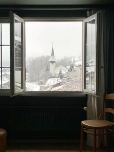 a window with a view of a snow covered church at Waterfall Views-Stylish Design-Big Comfy Bed in Lauterbrunnen