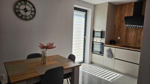 BobrówにあるModerný apartmán 2 s veľkou terasouのダイニングルーム(テーブル、壁掛け時計付)