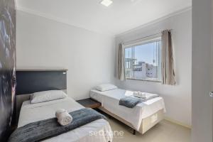 a bedroom with two beds and a window at Apto c/ Churrasqueira a 240m da Praia LUP0302 in Itajubá