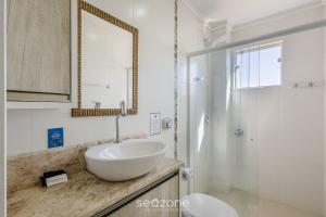 a white bathroom with a sink and a mirror at Apto c/ Churrasqueira a 240m da Praia LUP0302 in Itajubá +19 photos