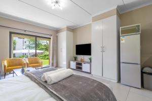 Un dormitorio con una cama grande y un televisor. en AlimamaSpaces - The View Studio, en Fourways