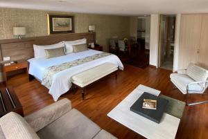 a bedroom with a large bed and a living room at Hotel Portón de la Cabrera in Bogotá