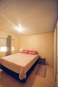 a bedroom with a bed with red pillows on it at Casa Espaçosa 3quartos Piscina Churrasqueira Estacionamento in Canoas