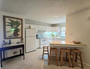 a kitchen with a white refrigerator and some bar stools at 9 Margate Gardens in Bridgetown