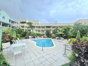 a pool with chairs and a table and a building at 9 Margate Gardens in Bridgetown