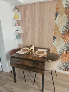 a wooden table with two plates on it with a chair at Maison Ethno Chic proche de Paris et d'Orly in Morangis