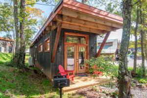 a tiny house with a porch and two red chairs at 1 Mile to Downtown West Jefferson Camping Cabin #1 in West Jefferson