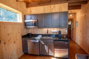 a kitchen with stainless steel appliances in a wooden cabin at 1 Mile to Downtown West Jefferson Camping Cabin #4 in West Jefferson