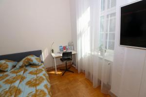 a bedroom with a bed and a desk and a flat screen tv at Altbauwohnung in Graz