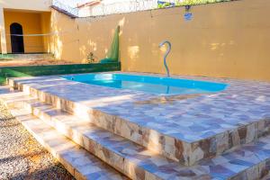 a swimming pool with a tile floor and a wall at Casa Alegria piscina churrasqueira in Montes Claros