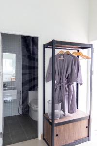 a bathroom with a toilet and a shelf with a robe at Serene Poolvilla hatyai in Hat Yai