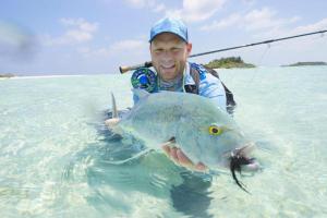 a man in the water with a fish in his hand at Fishing Tours Maldives in Thimarafushi