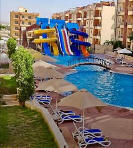 ein Wasserpark mit Wasserrutsche sowie Liegen und Sonnenschirmen in der Unterkunft الجناح الملكي بقرية ريتال فيو للعائلات الساحل الشمالي- العلمين in Dawwār Muḩammad Abū Shunaynah