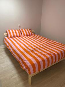 a bed with an orange and white striped comforter at Fogar en Soutelo in Forcarei