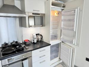 a small kitchen with white cabinets and a stove at Bright 2 Bed Flat with Balconies & Views in York City Centre in York