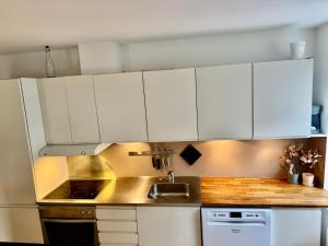 a kitchen with white cabinets and a sink at Central lejlighed med tag-terrasse in Aarhus