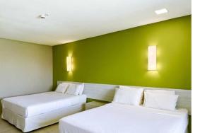 zwei Betten in einem Zimmer mit grüner Wand in der Unterkunft Enotel Porto de Galinhas All Inclusive in Porto De Galinhas + 93 Fotos