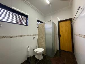 un bagno con wc e doccia con porta gialla di Belíssimo Apartamento Stella Maris -Casa de Carrara3 ad Andradina Altre 15 foto