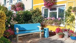 a blue bench in front of a house with flowers at Globe Guesthouse in Burry Port
