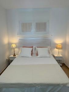 a bedroom with a white bed with two lamps at Apartamento Paraíso del Sol in Benajarafe