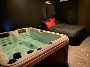 a bathroom with a jacuzzi tub with a bed at Le Cocoon Evasion Spa Jacuzzi in Annoeullin