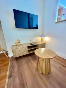 a living room with a table and a tv on a wall at Appartment Mal coiffé in Moulins