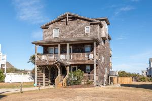 une vieille maison avec un porche et un balcon dans l'établissement Carolina Cottage, à Kitty Hawk