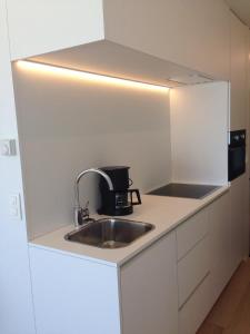 a white kitchen with a sink and a microwave at Studio Zeezicht in Ostend +11 photos
