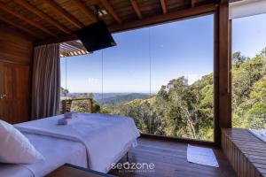 a bedroom with a bed and a large window at Cabana romântica com vista na serra VST033 in São Paulo dos Pinhais