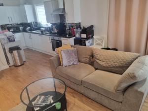 a living room with a couch and a kitchen at Fabulous two bedroom flat with concierge in Dagenham