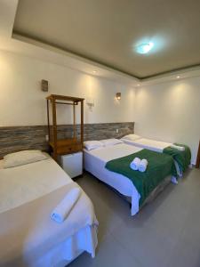 a bedroom with two beds with towels on them at Pousada Preciosa in Búzios