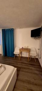 a room with a table and two chairs and a tv at Pensiunea Alina-Maria in Vîrfurile