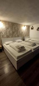 a large white bed in a bedroom with a wall at Pensiunea Alina-Maria in Vîrfurile