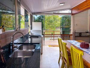 a kitchen with a sink and a table with yellow chairs at Chalé do Lago 1137 in Itu