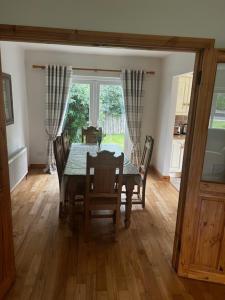 a dining room with a table and chairs and a window at 49 Dunalinn Culdaff in Balnacart +1 photo